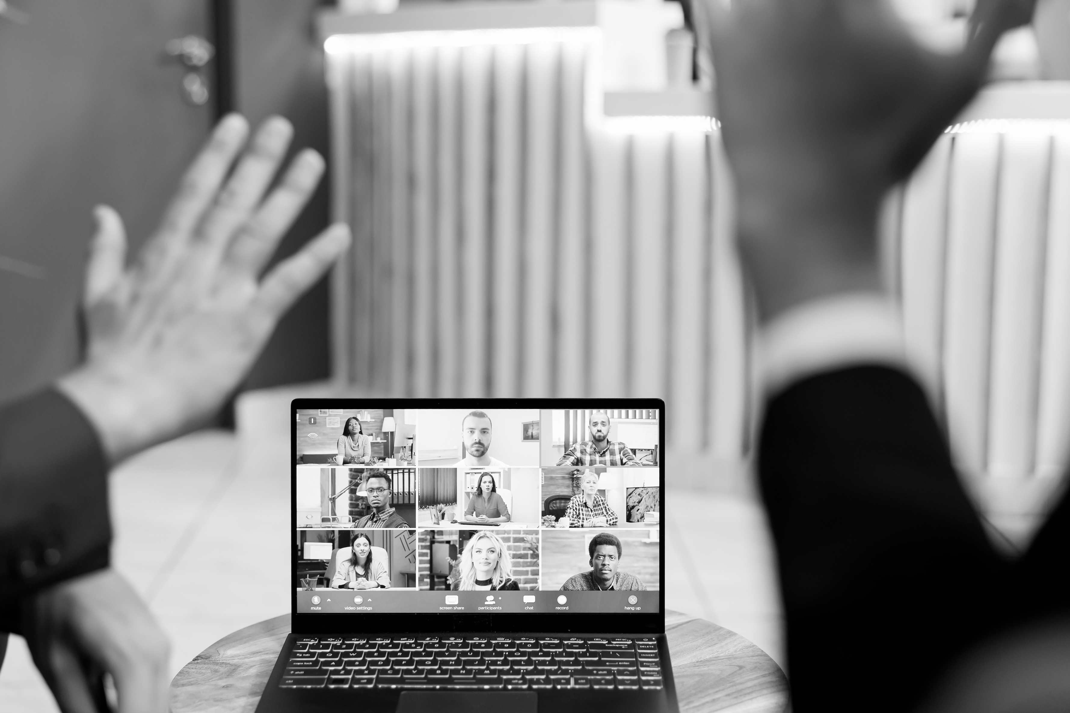 virtual conference call with hands waving to laptop screen
